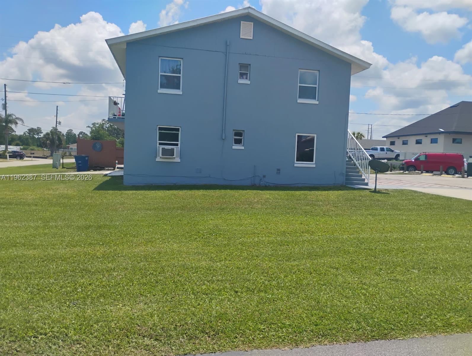 A two-story blue building with a lawn and an outdoor staircase stands under a sky — 4131 Commercial Dr, Sebring FL 33870, SEBRING, FL