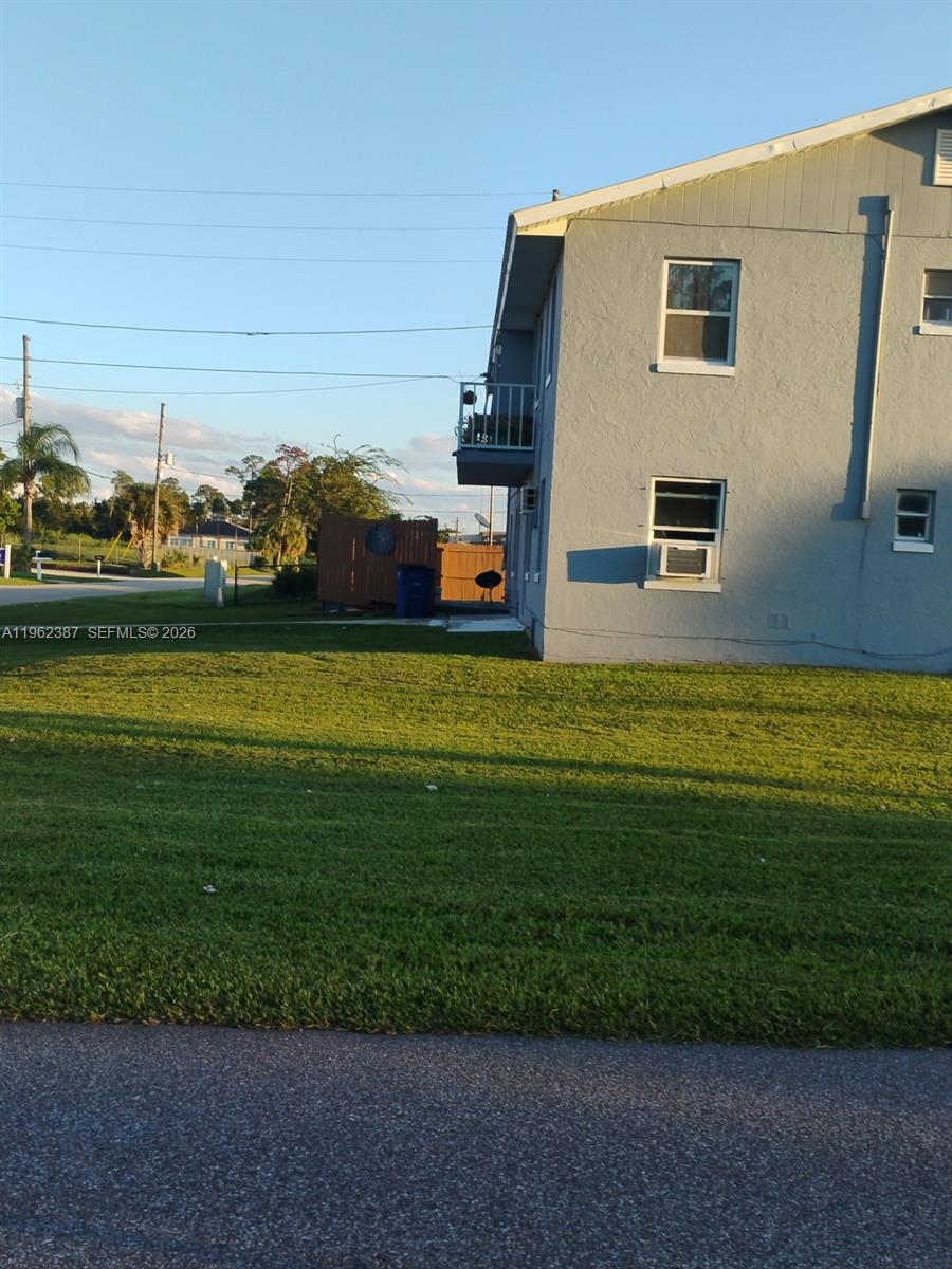 A side view of a two-story gray stucco apartment building with a small balcony — 4131 Commercial Dr, Sebring FL 33870, SEBRING, FL