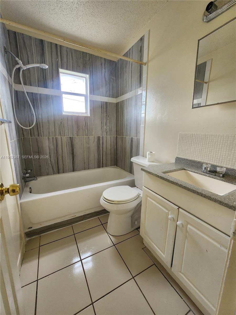 A bathroom features a tiled tub-shower combination, a white toilet, and a vanity with sink — 4131 Commercial Dr, Sebring FL 33870, SEBRING, FL