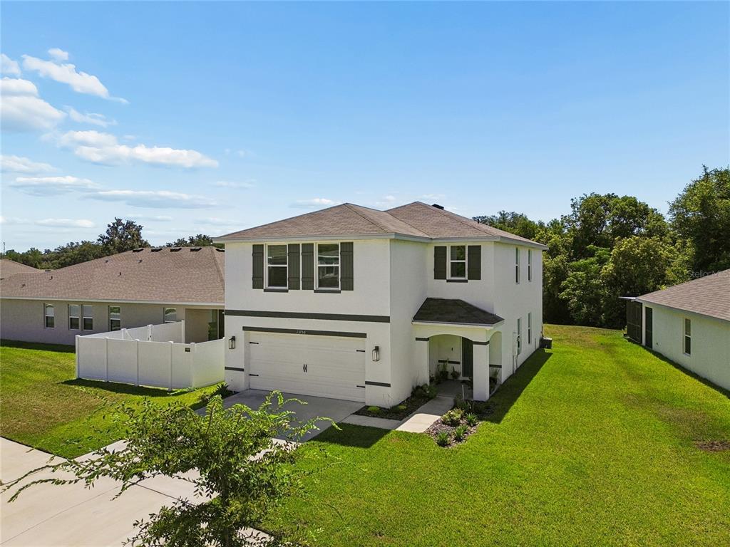 An exterior view of a two-story suburban house with a white stucco facade and garage — 13756 WHISKEY DAISY DRIVE, DADE CITY, FL