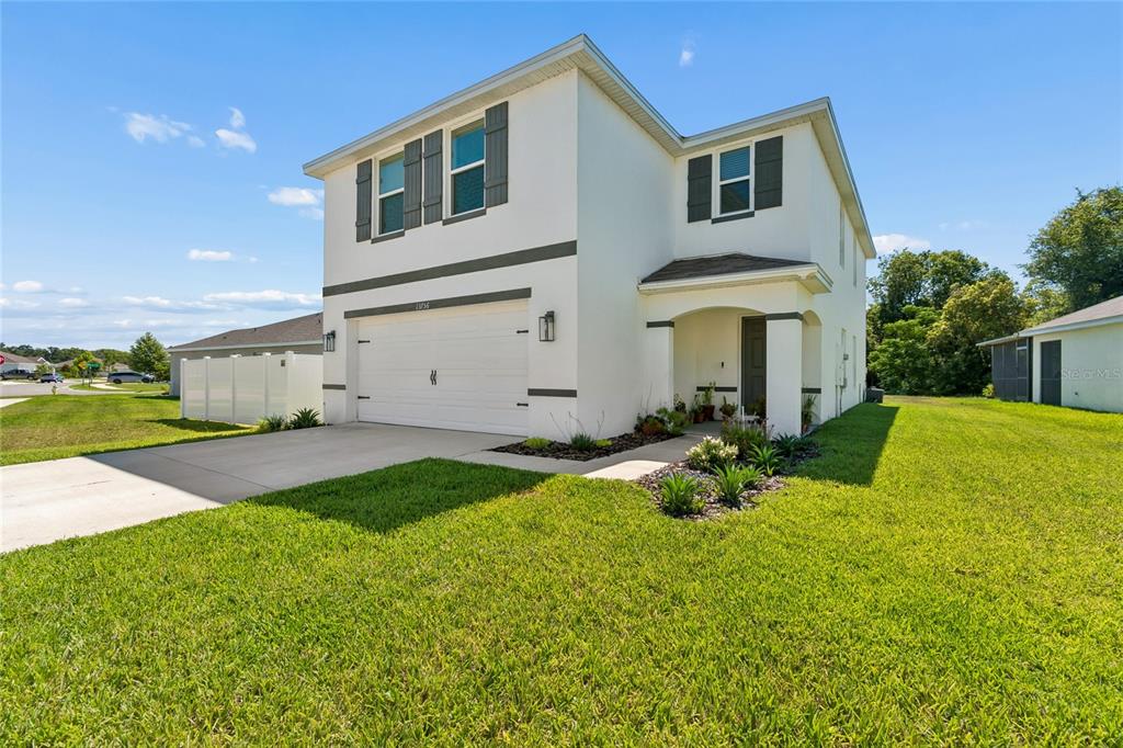 A two-story white house with a two-car garage and a covered entryway — 13756 WHISKEY DAISY DRIVE, DADE CITY, FL