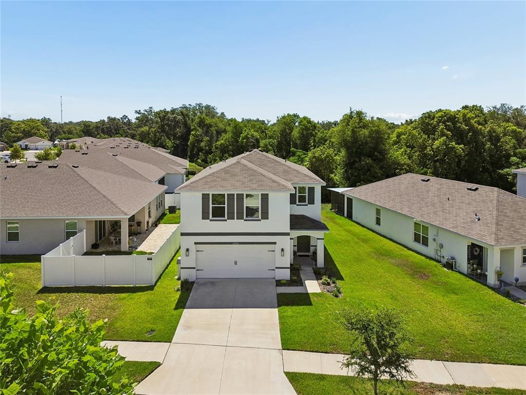 An aerial view of a two-story suburban house with a white exterior and attached garage — 13756 WHISKEY DAISY DRIVE, DADE CITY, FL