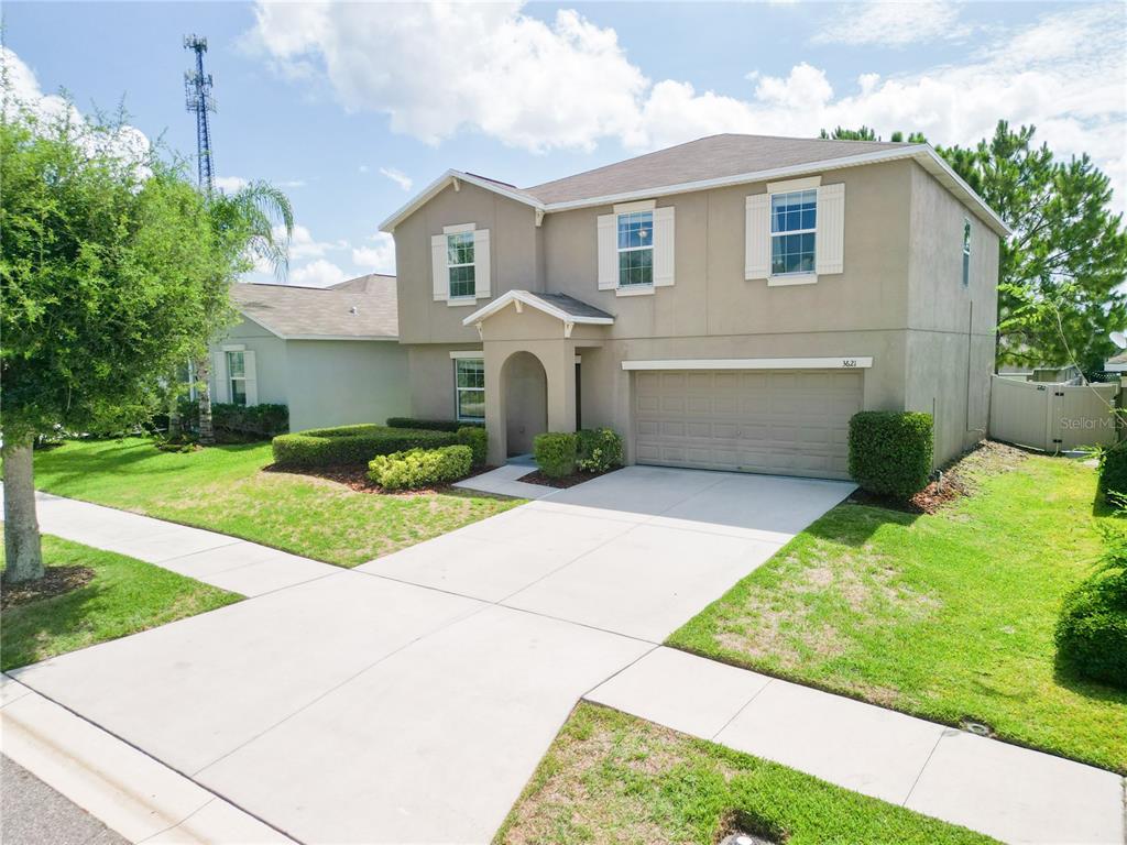 A two-story suburban house with a beige stucco exterior, a two-car garage, and a driveway — 3621 KEARSNEY ABBEY CIRCLE, DOVER, FL