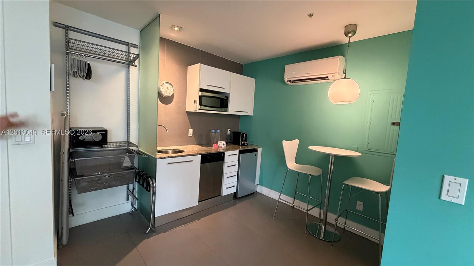 A small kitchen area features white cabinets, a dining table with two chairs, and teal walls — 1816 Meridian Ave # 9, Miami Beach FL 33139, MIAMI BEACH, FL