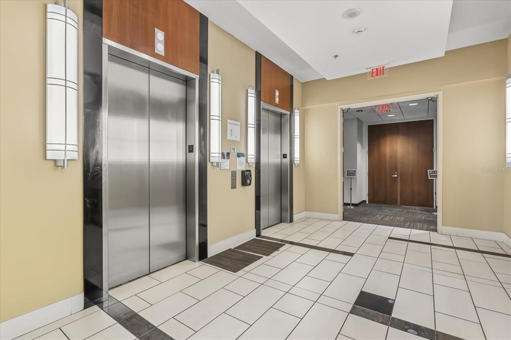 An elevator lobby features two stainless steel elevator doors, tile flooring, and a wooden exit door — 189 S ORANGE AVENUE UNIT 1900-1970, ORLANDO, FL
