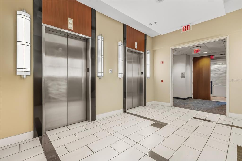 An elevator lobby features two stainless steel elevators, tiled floors, and an open doorway — 189 S ORANGE AVENUE UNIT 1900-1970, ORLANDO, FL