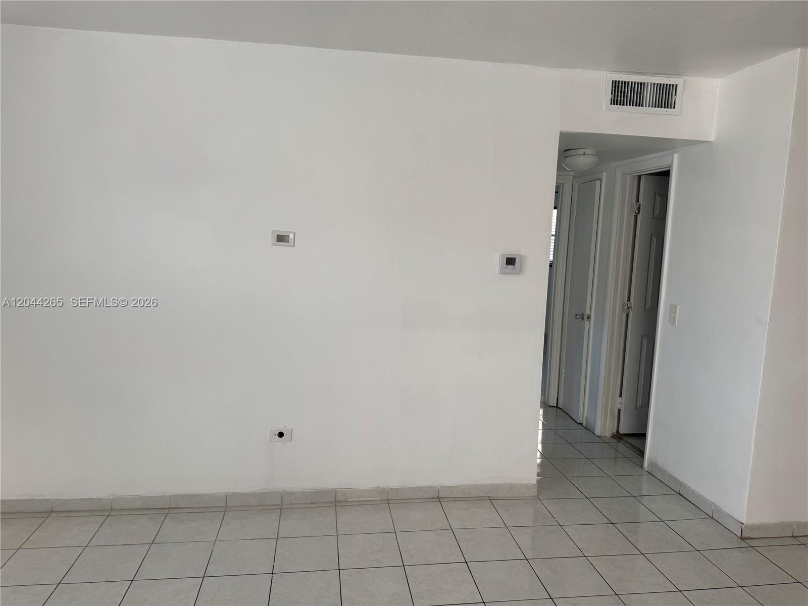 A white-walled room features light-colored floor tiles and a doorway leading to a hallway — 1765 Venice Ln # 4E, North Miami FL 33181, NORTH MIAMI, FL