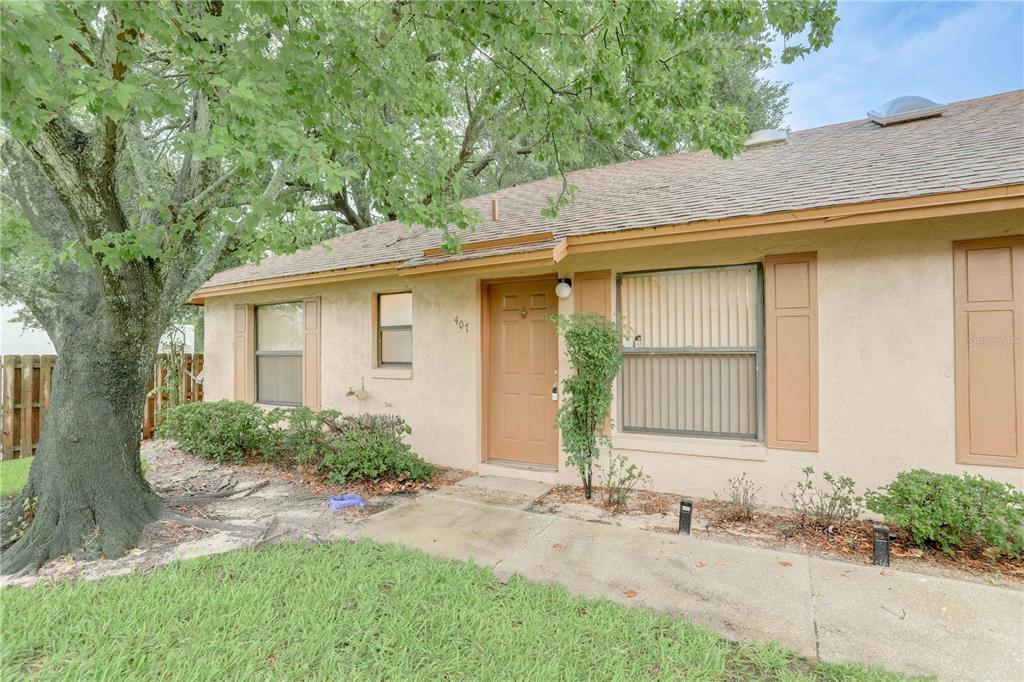 A single-story house exterior with a tan stucco facade, brown shutters, and a front walkway — 407 DOUGLAS WAY UNIT 66, WINTER GARDEN, FL