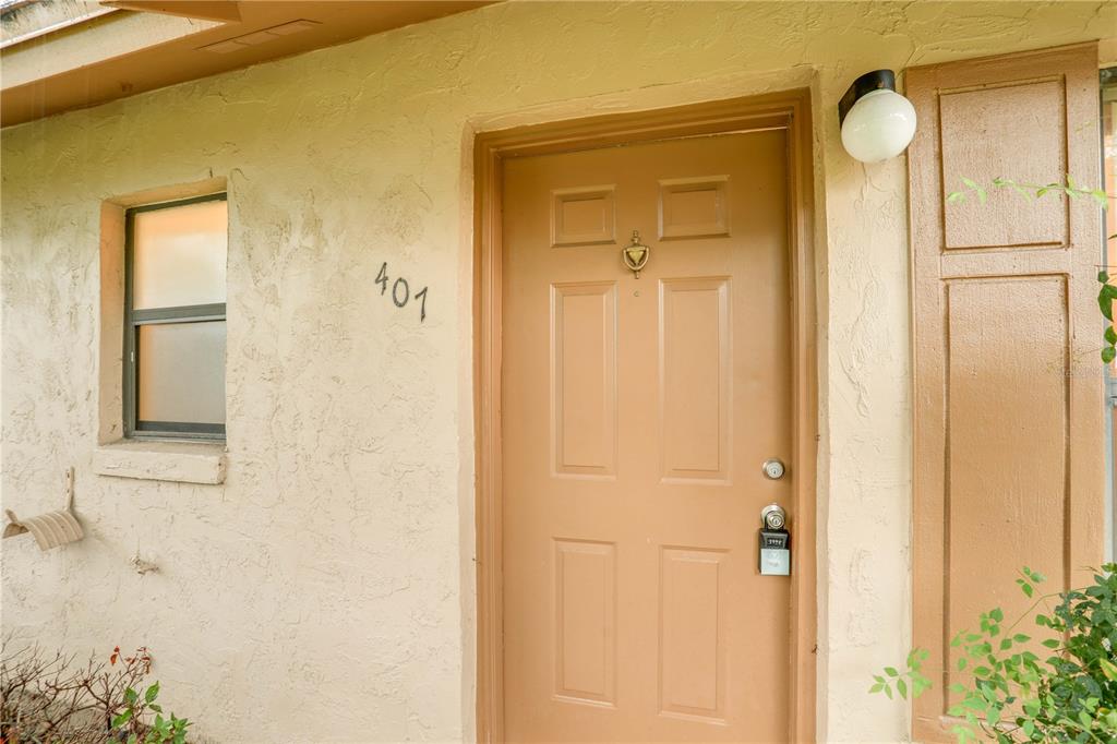 A tan exterior wall features a brown door with a lockbox and the number 401 — 407 DOUGLAS WAY UNIT 66, WINTER GARDEN, FL