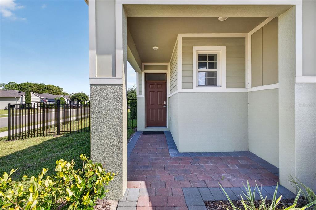 A covered entryway features a brick paver walkway leading to a brown front door — 17386 BLAZING STAR CIRCLE, CLERMONT, FL