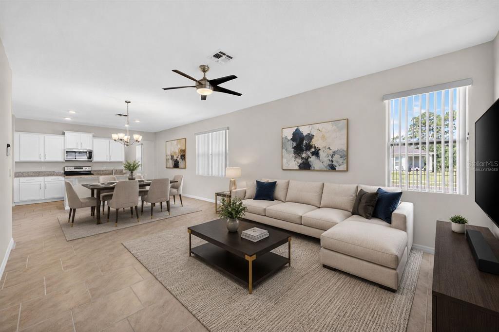 An open-concept living and dining area features a sectional sofa, dining table, and kitchen — 17386 BLAZING STAR CIRCLE, CLERMONT, FL