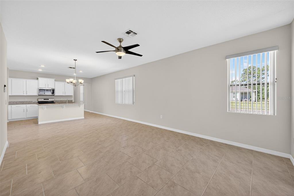 An open-concept living area with tile flooring, a ceiling fan, and an adjacent kitchen — 17386 BLAZING STAR CIRCLE, CLERMONT, FL