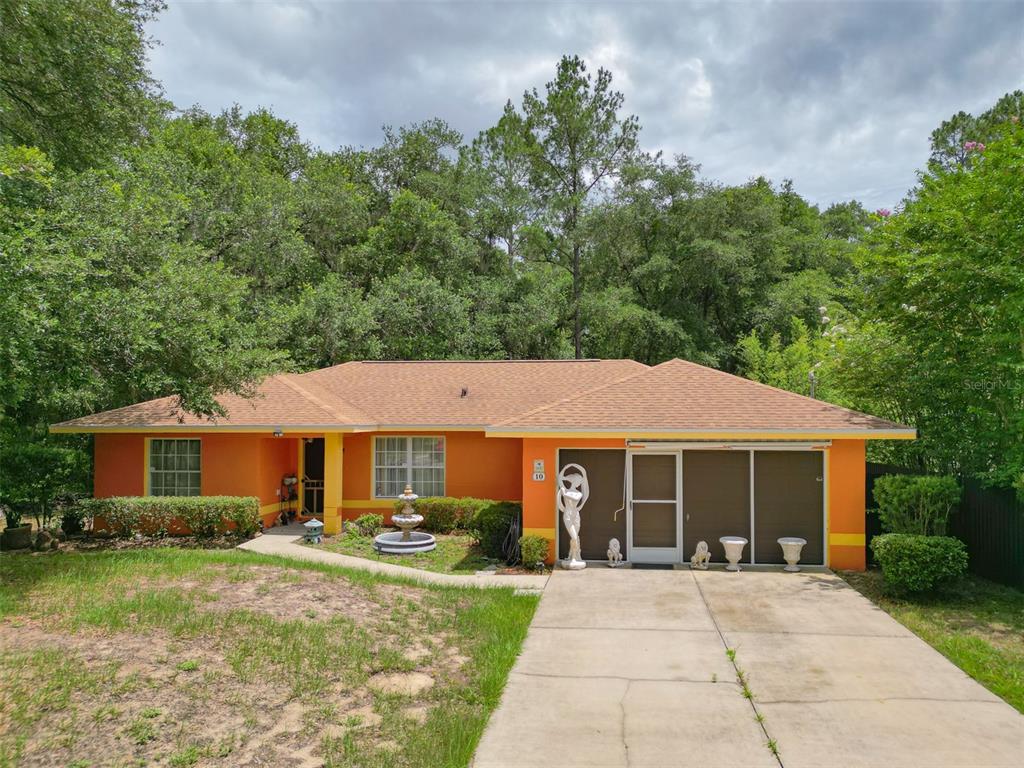 A single-story orange house with a brown shingled roof and a concrete driveway — 10 SEQUOIA DRIVE TRACE, OCKLAWAHA, FL