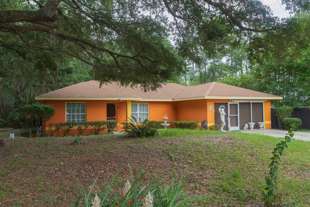 A single-story orange house with a brown roof sits on a grassy lot under trees — 10 SEQUOIA DRIVE TRACE, OCKLAWAHA, FL