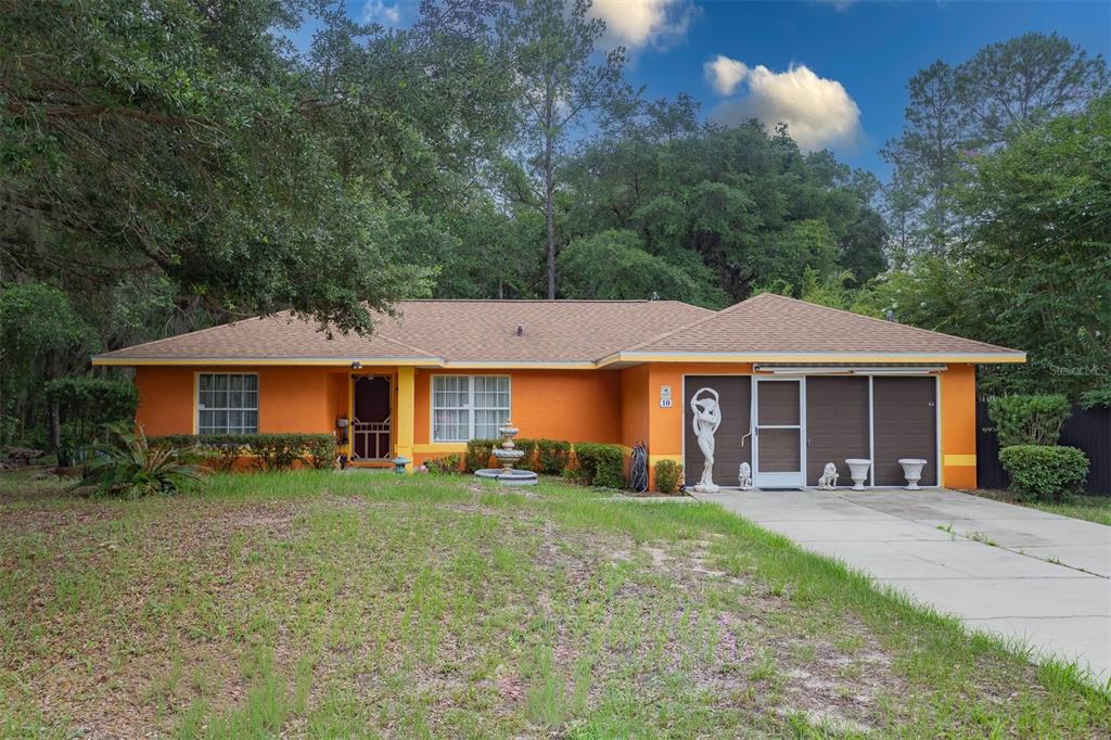 A single-story orange house with a brown roof, a front lawn, and a concrete driveway — 10 SEQUOIA DRIVE TRACE, OCKLAWAHA, FL