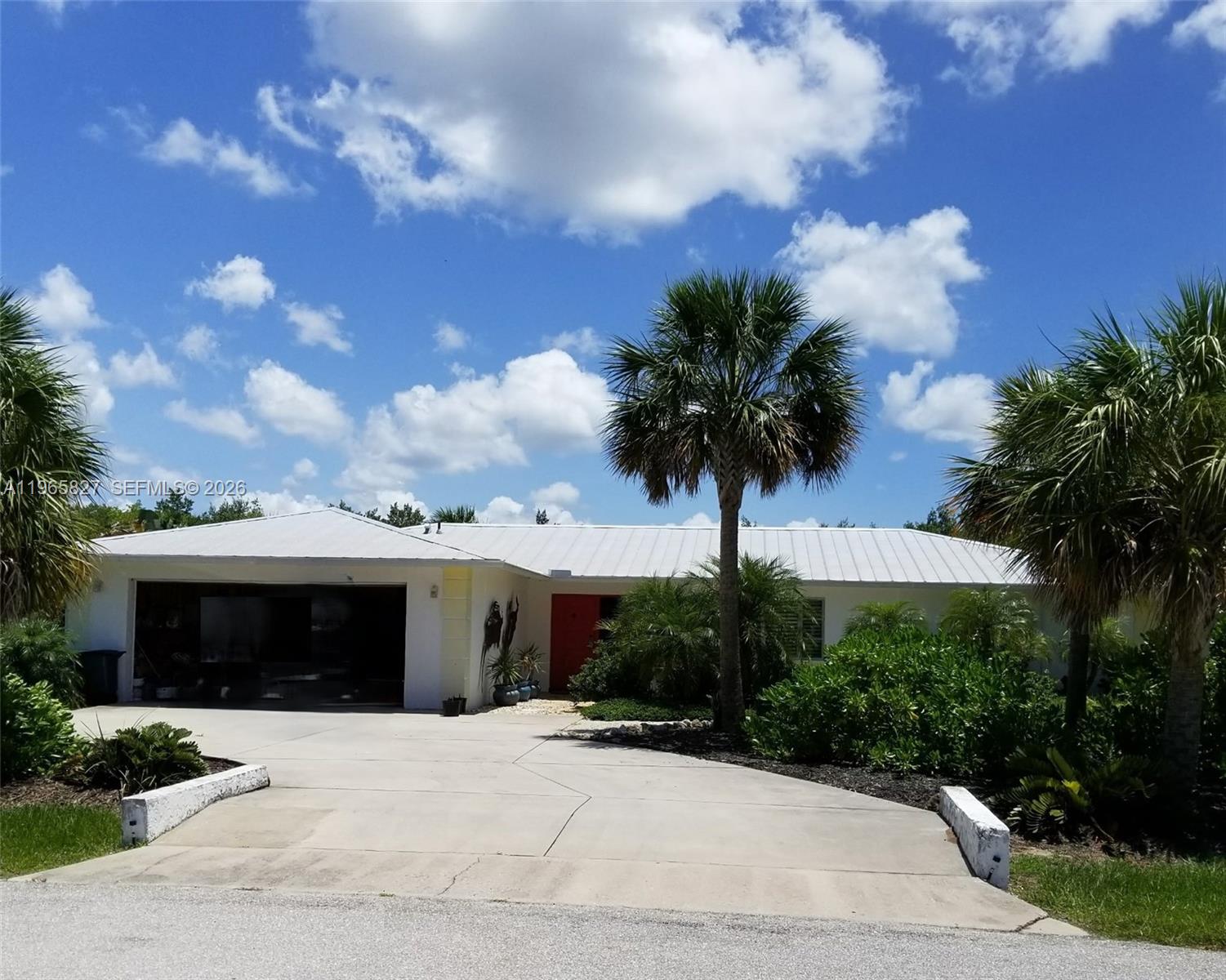 A white single-story house features a metal roof, a garage, and a red front door — OTHER CITY - IN THE STATE OF FLORIDA, FL
