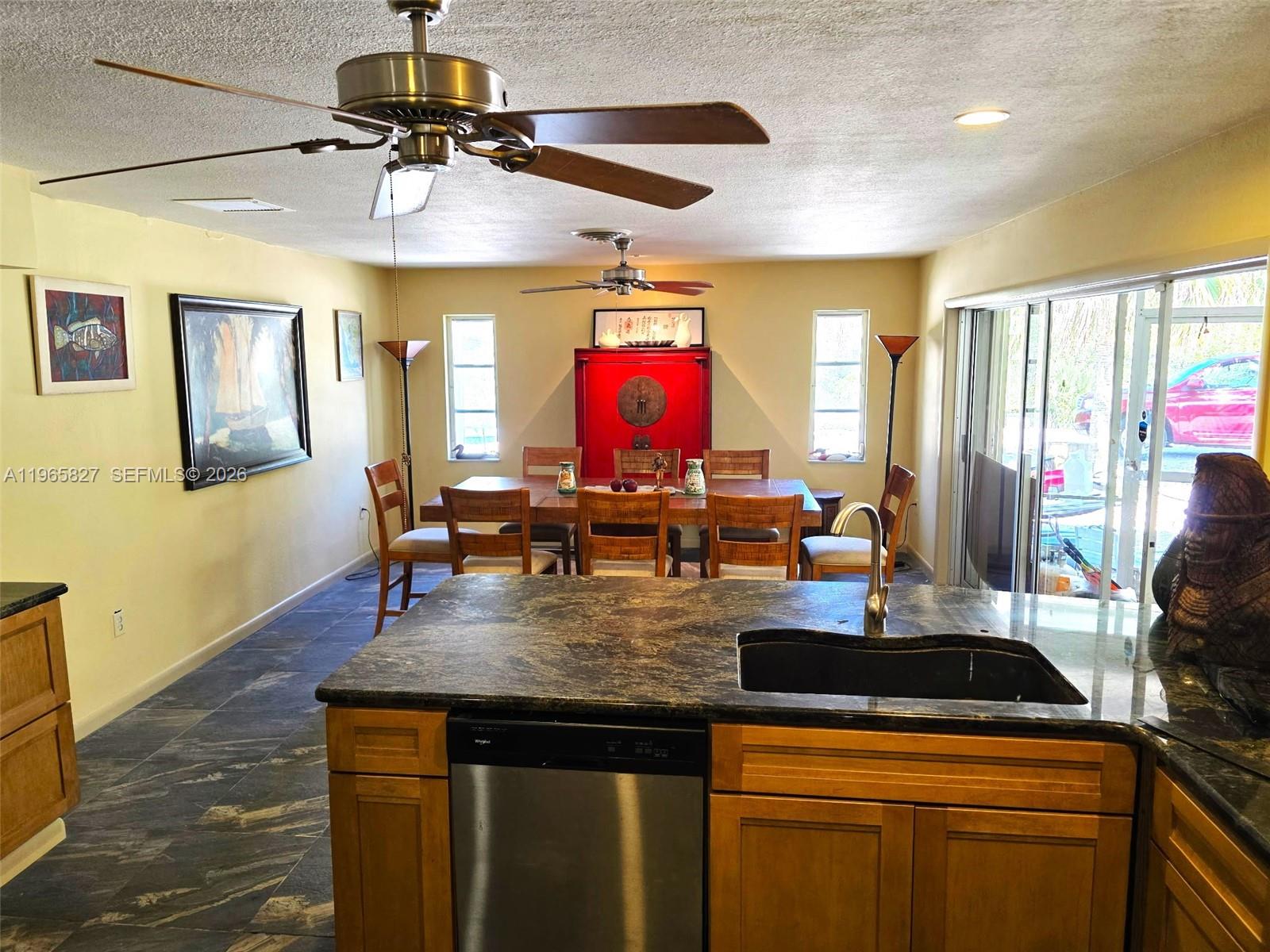 A kitchen island with a dark countertop overlooks a dining area with wooden furniture — OTHER CITY - IN THE STATE OF FLORIDA, FL
