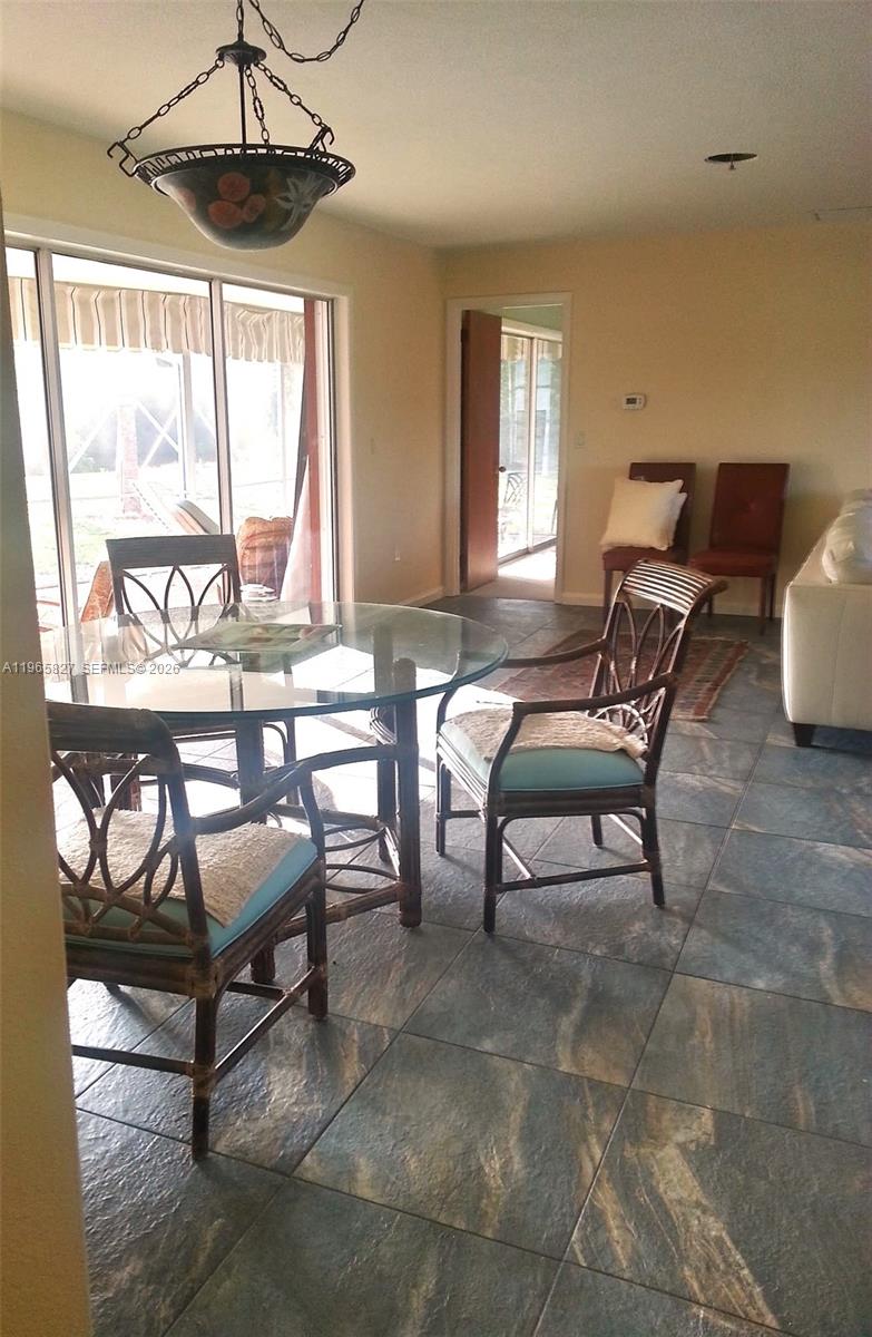 A dining area features a glass table, rattan chairs, tile flooring, and a sliding glass door — OTHER CITY - IN THE STATE OF FLORIDA, FL