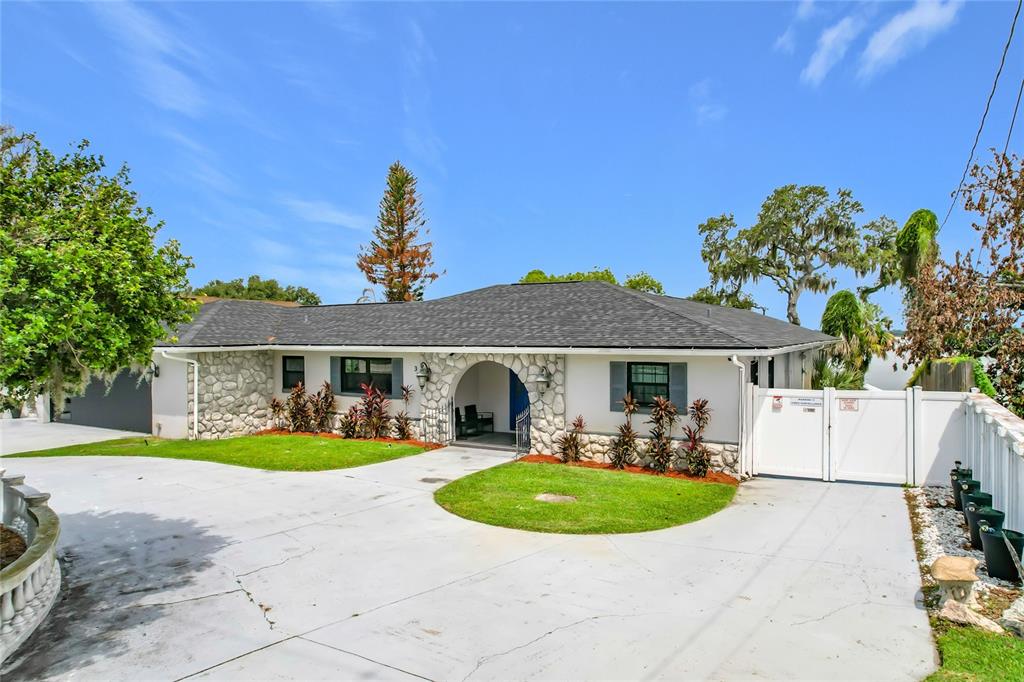 A single-story house with a stone facade, arched entryway, and a large concrete driveway — 331 BAY STREET, AUBURNDALE, FL
