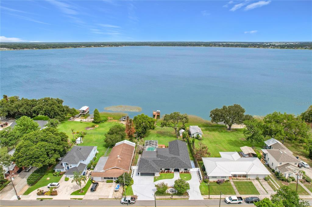 An aerial view shows several waterfront houses with green lawns along a large lake — 331 BAY STREET, AUBURNDALE, FL