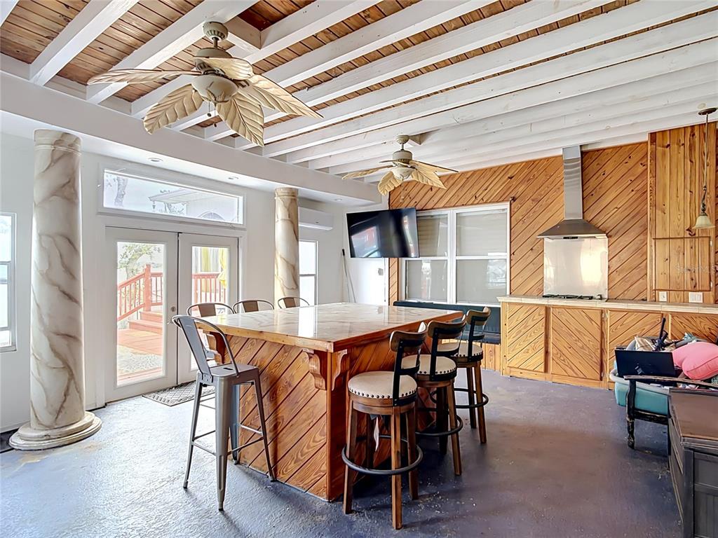 A rustic outdoor kitchen features a large wooden island, bar stools, and palm-leaf ceiling fans — 331 BAY STREET, AUBURNDALE, FL