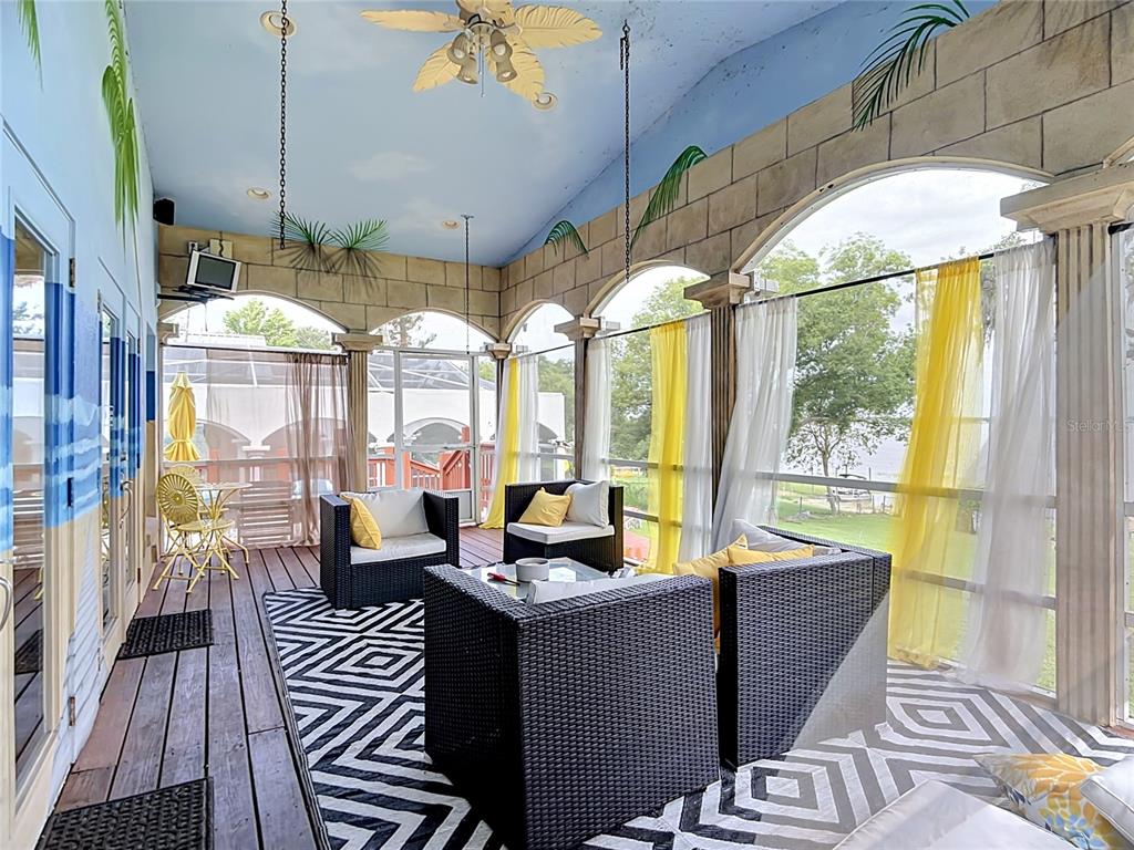 A screened-in porch features wicker furniture, a patterned rug, and a painted sky ceiling — 331 BAY STREET, AUBURNDALE, FL