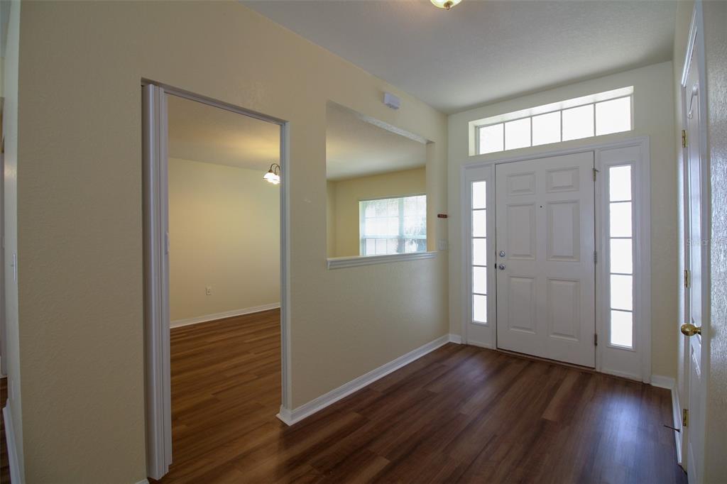An entryway with wood-look flooring, a white front door, and an open wall cutout — 6719 HIGHLANDS CREEK BOULEVARD, LAKELAND, FL