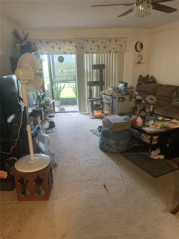 A living room with beige carpet, a ceiling fan, a sliding glass door, and furniture — 1064 LOTUS PARKWAY UNIT 915, ALTAMONTE SPRINGS, FL