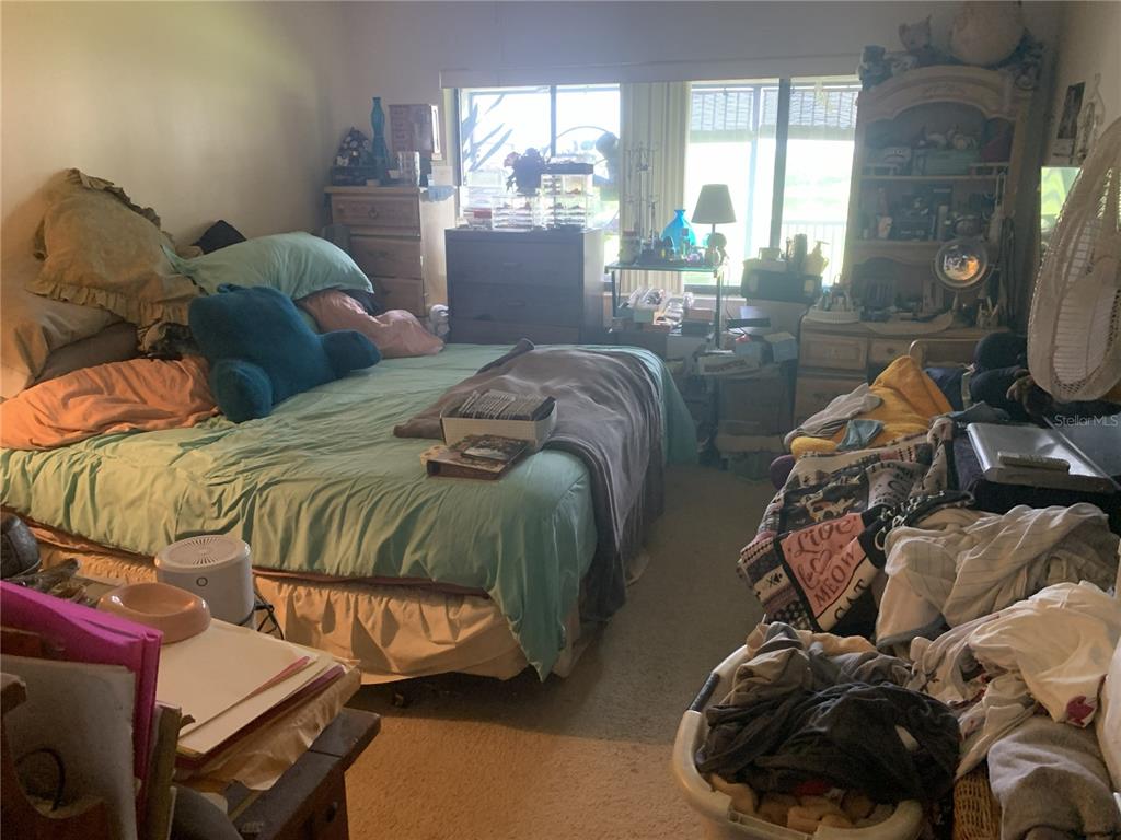 A bedroom with a bed, dresser, shelving unit, and laundry basket filled with clothes — 1064 LOTUS PARKWAY UNIT 915, ALTAMONTE SPRINGS, FL