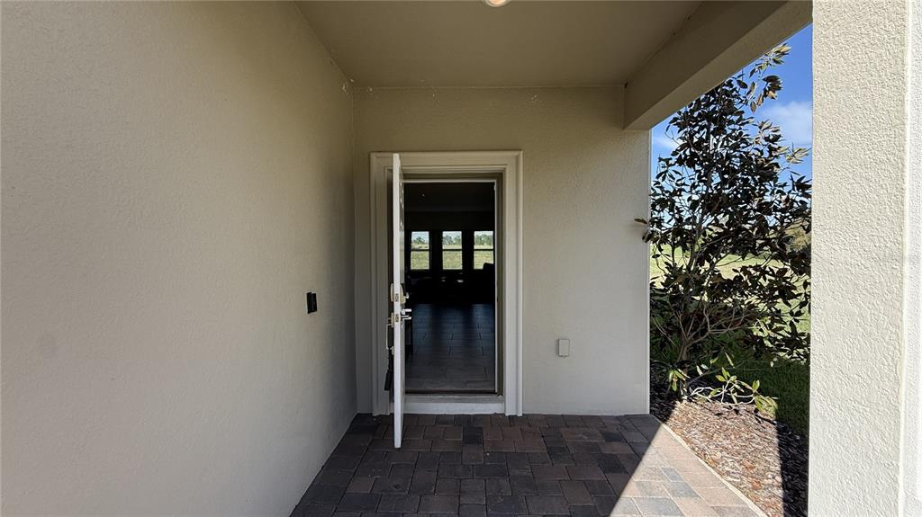 A paved patio leads to an open doorway revealing a view through a home's interior — 1055 BLACKWOLF RUN ROAD, DAVENPORT, FL