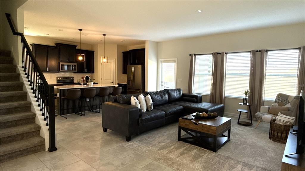 An open-concept living room features a kitchen with dark cabinetry and a sectional sofa — 1055 BLACKWOLF RUN ROAD, DAVENPORT, FL