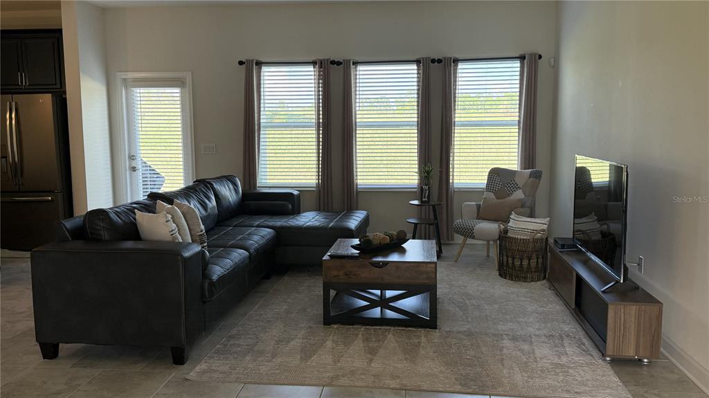 A living room features a black sectional sofa, a wooden coffee table, and a television — 1055 BLACKWOLF RUN ROAD, DAVENPORT, FL