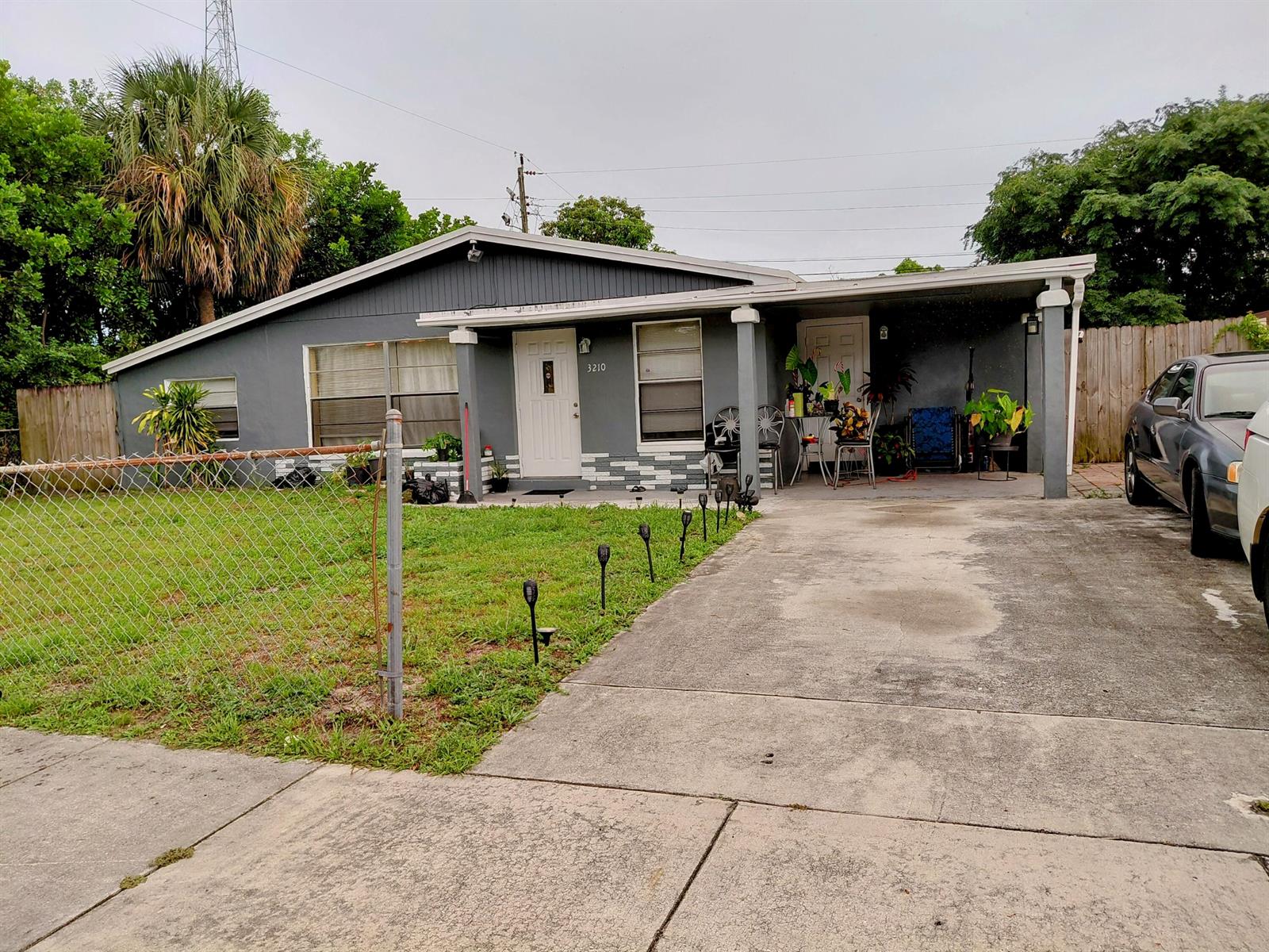 A gray single-story house with a front porch, carport, and a chain-link fence — 3210 NW 18th Place, Lauderhill FL 33311, LAUDERHILL, FL