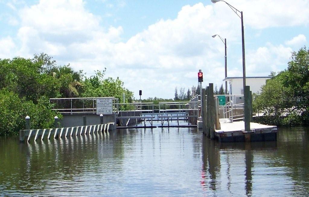 A boat lock structure with a red signal light sits on a waterway surrounded by mangroves — 13464 TRASCORO LANE, PORT CHARLOTTE, FL