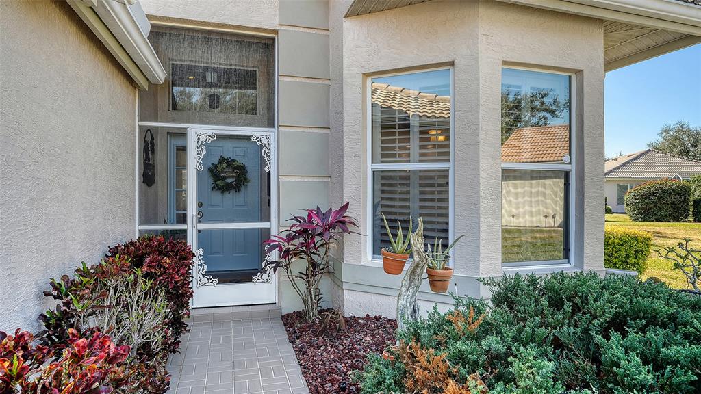 The exterior view shows a light-colored home entrance with a screen door and landscaping — 5811 WHITE OAK BAYOU COURT, BRADENTON, FL