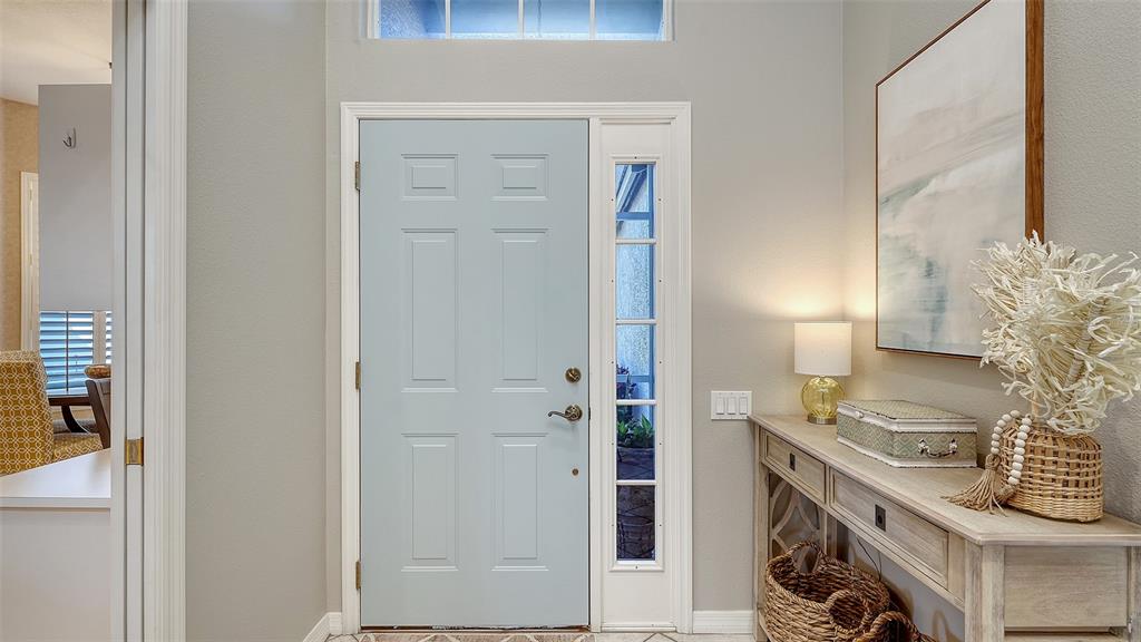 A light blue front door with a sidelight window stands in a neutral-toned entryway — 5811 WHITE OAK BAYOU COURT, BRADENTON, FL