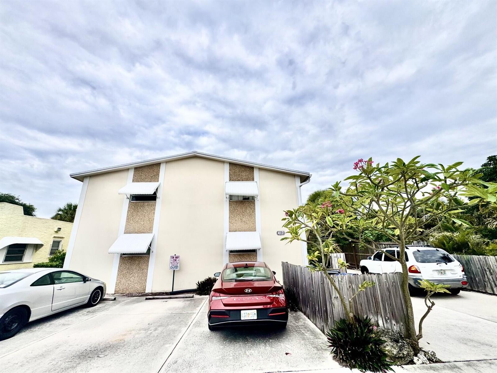 A two-story apartment building exterior with a red sedan parked in the driveway — 417 N K Street # 1a, FL 33460, FL