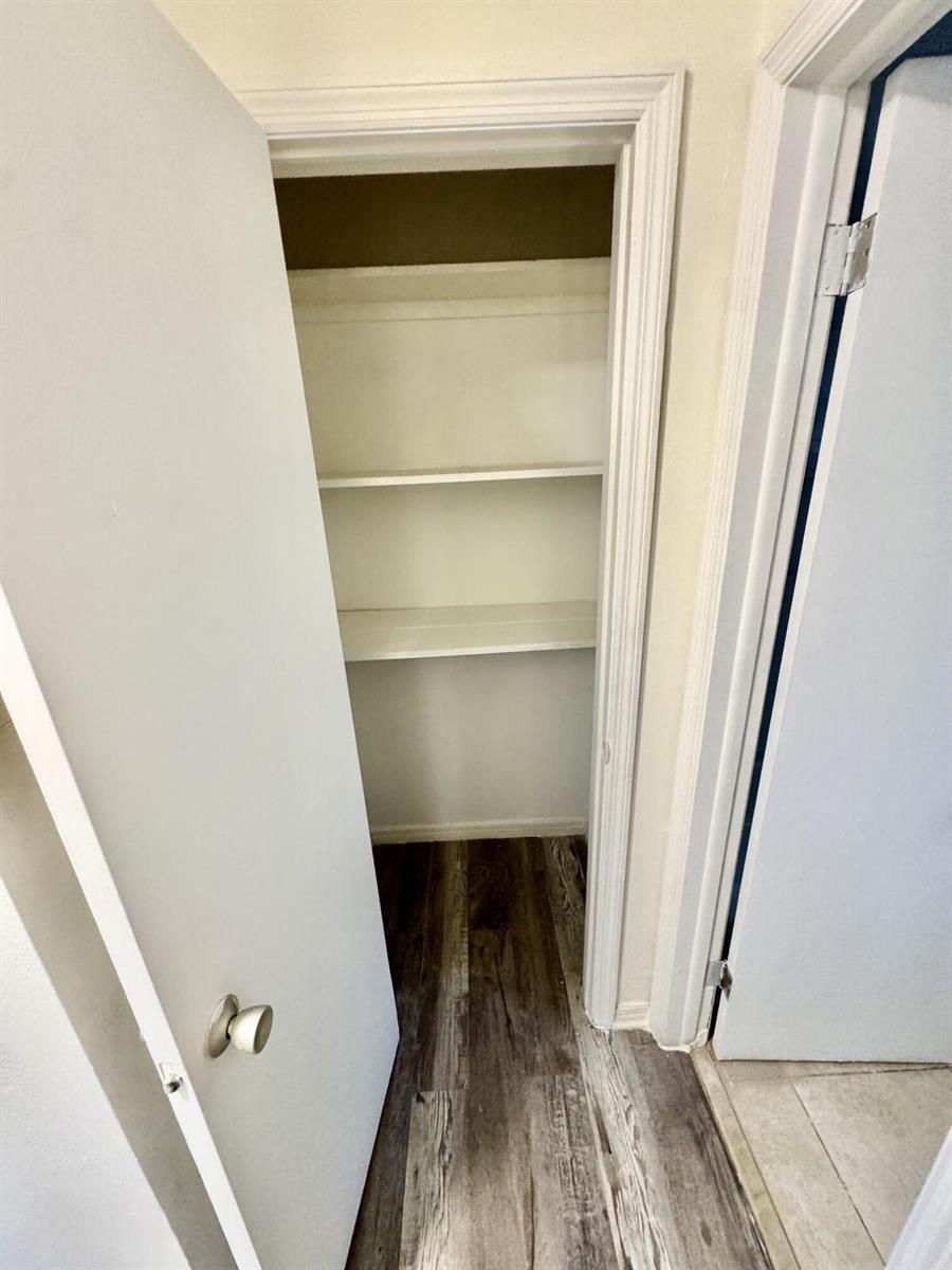 A small closet with white shelving and wood-look flooring viewed through an open door — 417 N K Street # 1a, FL 33460, FL