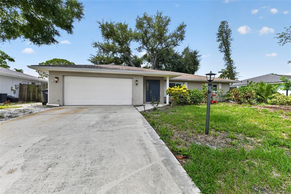 A single-story house with a white garage door, dark front door, and a concrete driveway — 7207 14TH AVENUE NW, BRADENTON, FL