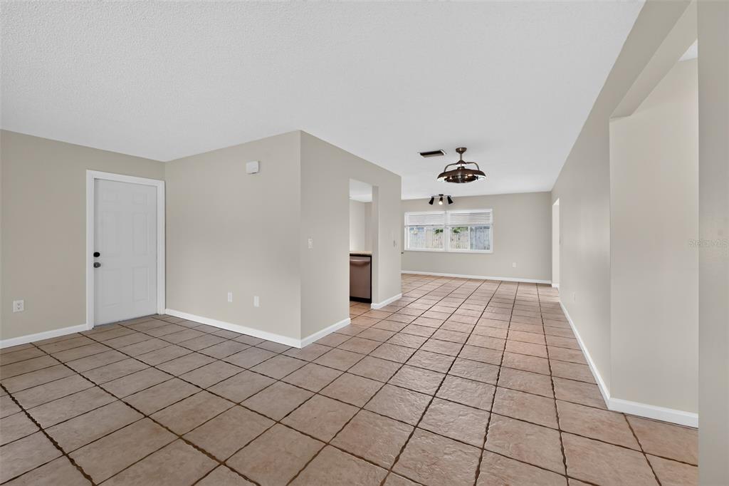 A tiled living area features a white door, a kitchen pass-through, and a ceiling fan — 7207 14TH AVENUE NW, BRADENTON, FL