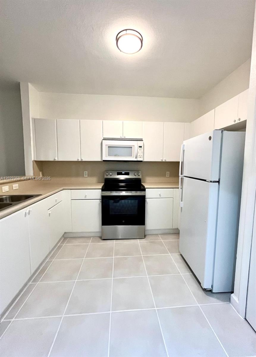A kitchen features white cabinets, stainless steel appliances, and light-colored tile flooring — 4284 SW 157th Ave # 127, Miramar FL 33027, MIRAMAR, FL