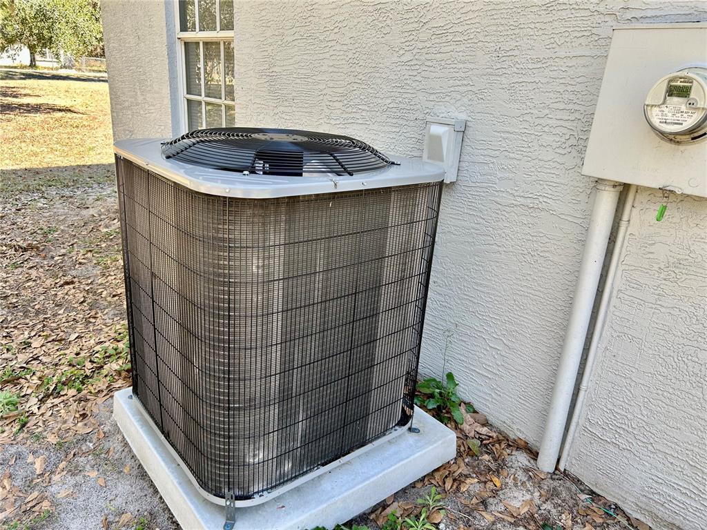 An outdoor air conditioning unit sits on a concrete pad next to a house exterior — 3456 ELM STREET, ZOLFO SPRINGS, FL