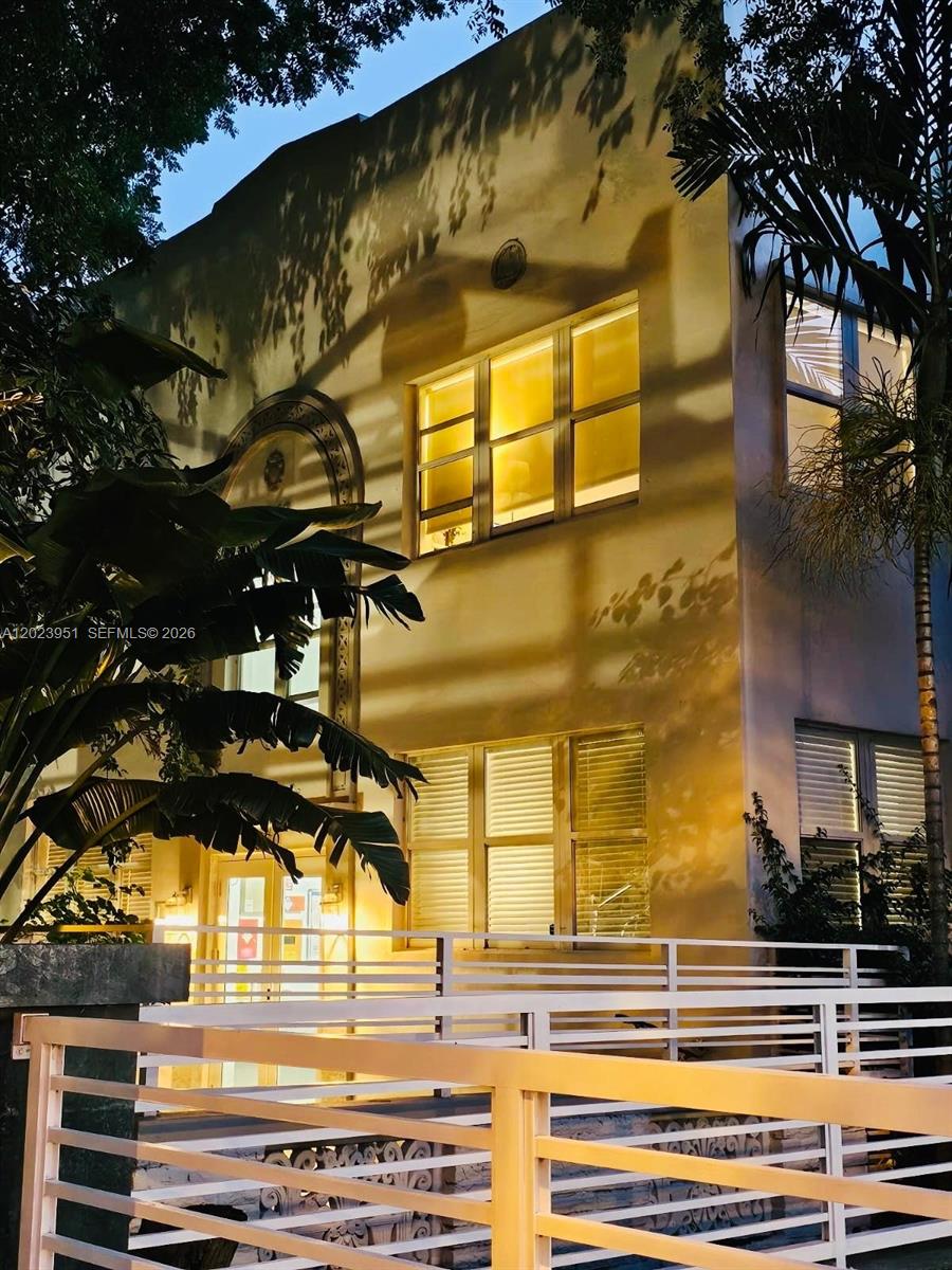 A two-story stucco building with arched architectural details and large windows at dusk — 1550 Drexel Ave # 202, Miami Beach FL 33139, MIAMI BEACH, FL