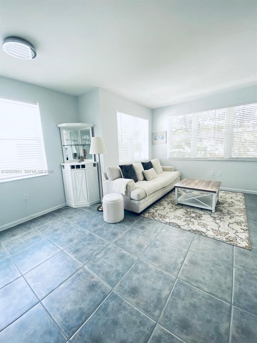 A living room features light-colored tile flooring, a white sofa, and a corner display cabinet — 1550 Drexel Ave # 202, Miami Beach FL 33139, MIAMI BEACH, FL