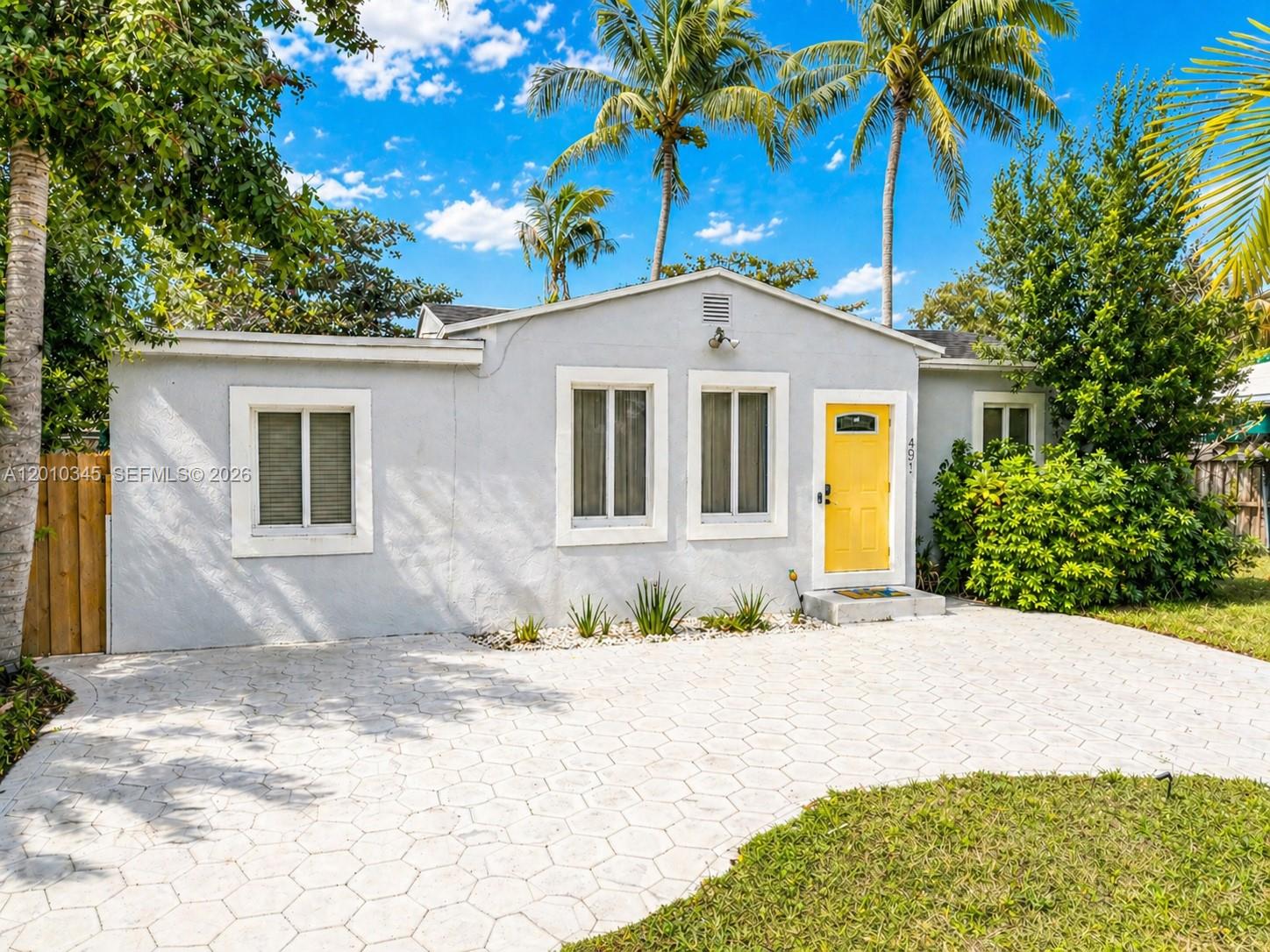 A single-story house with a yellow front door and a paved driveway under palm trees — 491 NW 108th Ter, Miami FL 33168, MIAMI, FL