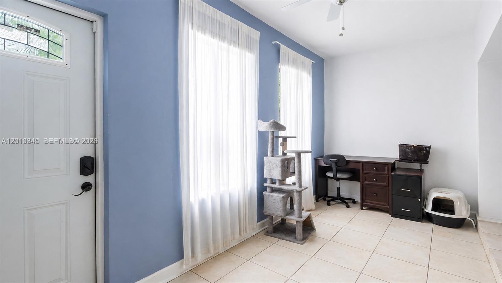 A room with blue walls, tile flooring, a desk, and a cat tree — 491 NW 108th Ter, Miami FL 33168, MIAMI, FL