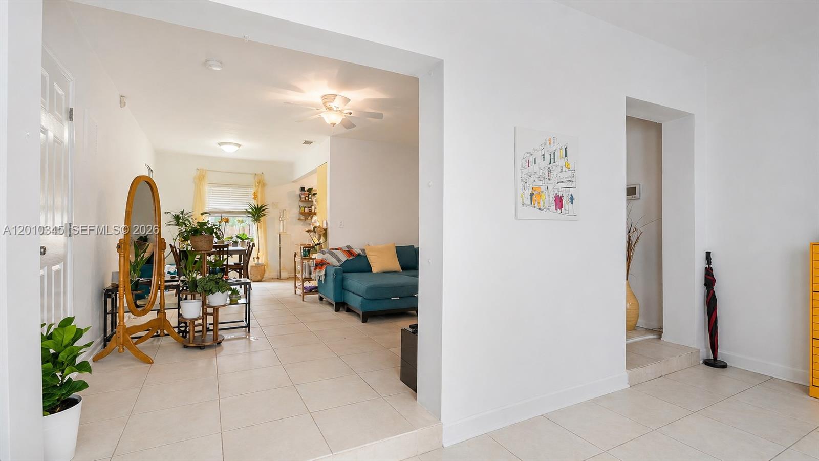 A bright living and dining area features white walls, tile flooring, and a blue sofa — 491 NW 108th Ter, Miami FL 33168, MIAMI, FL