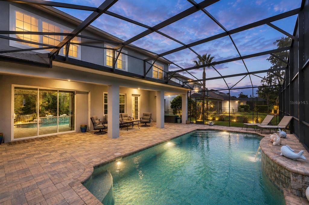 A screened-in patio features a swimming pool with a water feature and paver flooring — 14067 JOMATT LOOP, WINTER GARDEN, FL