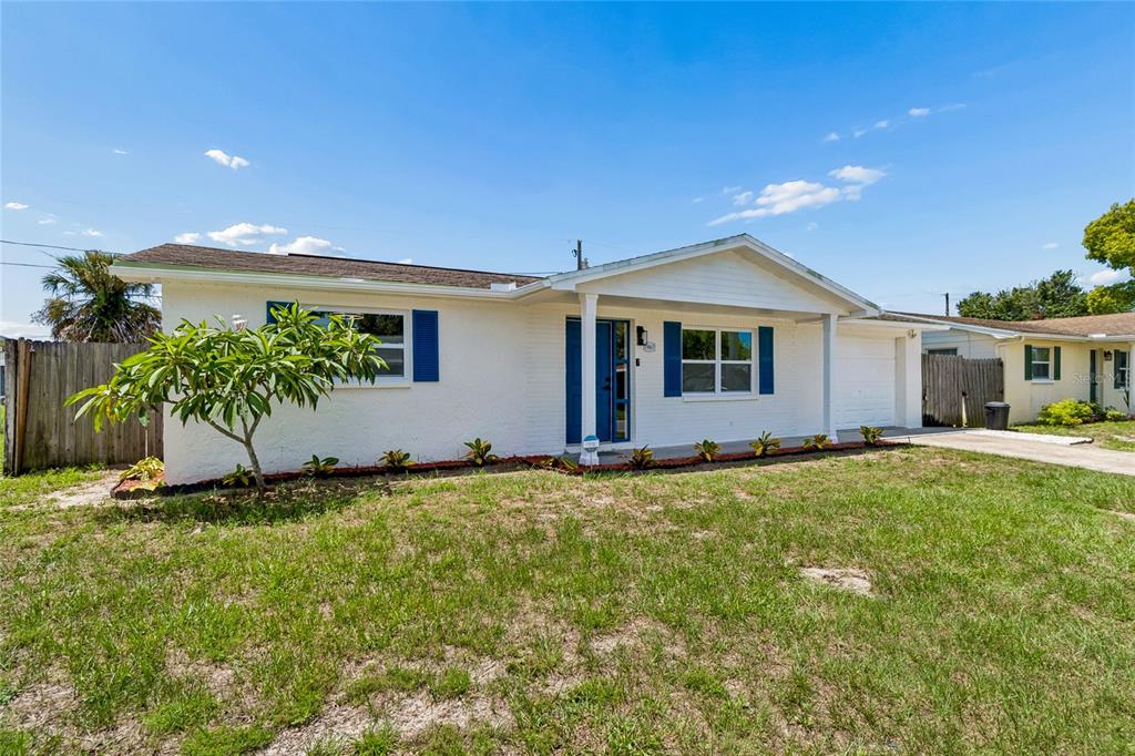 A single-story white house with blue shutters and a front porch under a blue sky — 1467 CLASSIC DRIVE, HOLIDAY, FL