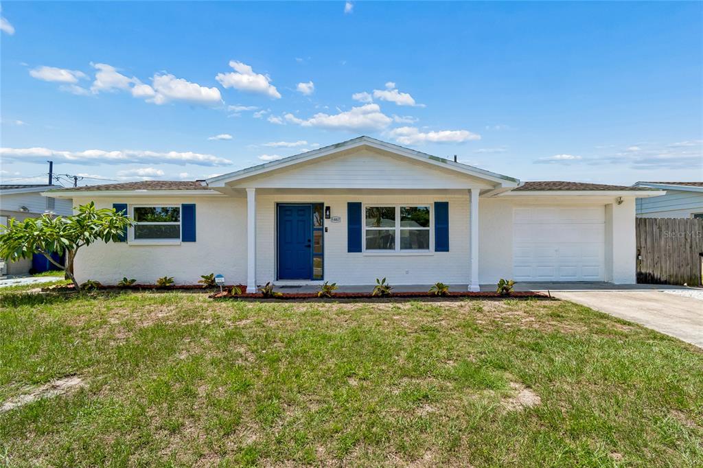 A single-story white brick house with a blue front door and an attached garage — 1467 CLASSIC DRIVE, HOLIDAY, FL
